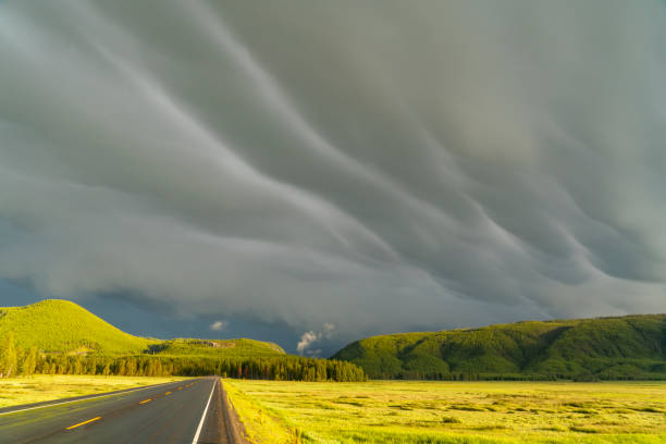 dramatic storm cloud sky above mountain and country road under sunlight