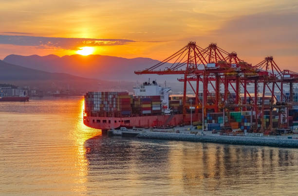 istock Logistics of Container Cargo ship with working crane bridge in shipyard during sunrise 2173842639