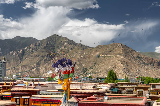 Bajiaojie, Lhasa, Tibet, China - May 21, 2022: Top angle view of flags on rooftop of a building against blue sky with window and white wall