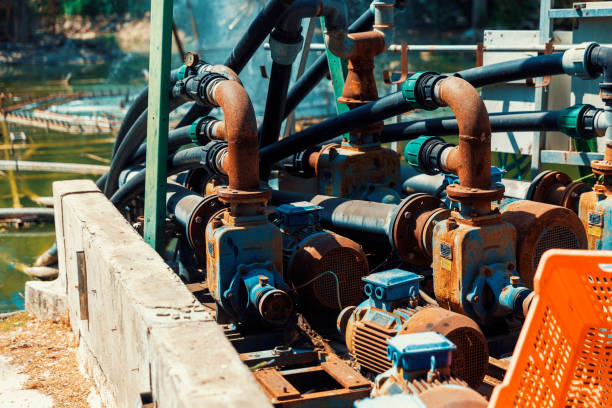 Close-up of an industrial water pump system with multiple pipes and motors used for irrigation or water management in an outdoor setting.