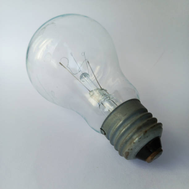 closeup of an old burning light bulb, a carton as background is illuminated, lit with a warm yellow or orange light