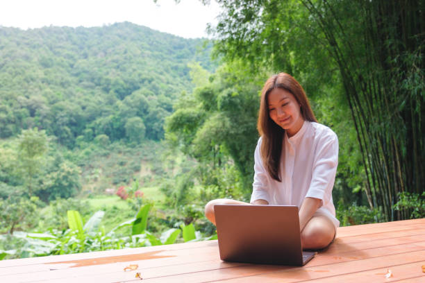 istock Portrait image of a woman using and working on laptop computer while sitting on balcony with a beautiful nature view 2173856723
