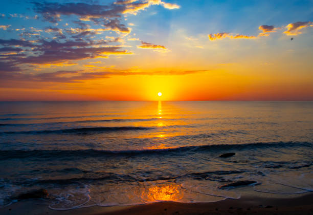 Stunning scene of dusk or sunrise over a water horizon in sea from a sandy beach in Torremolinos, Malaga, Andalusia, Spain