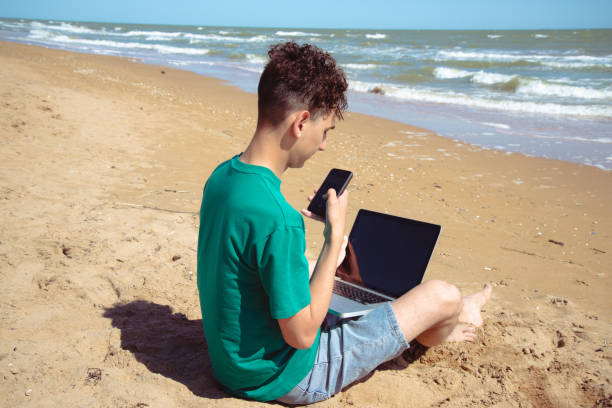 istock A young attractive man relaxes and studies by the sea. 2173869255