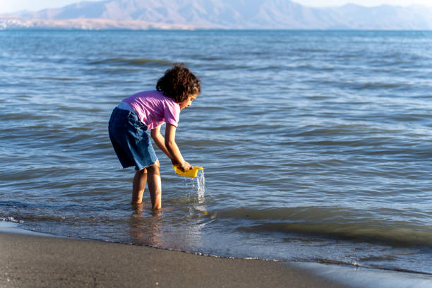 Little girl playing with toys at tropical beach. Family summer vacation. Travel with young children. Children, summer and Skin care concept.