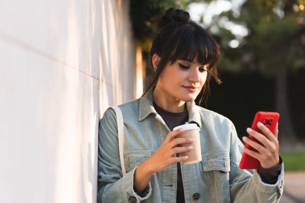istock A woman is looking at her phone while holding a coffee cup. Lifestyles 2173876208