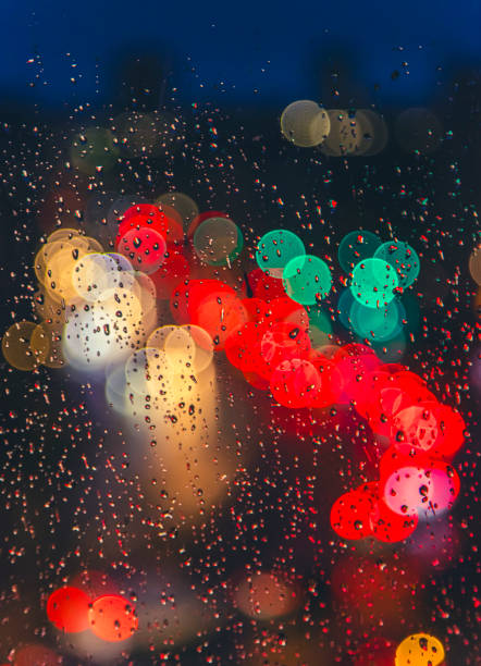 rain drops on window surface with colorful traffic bokeh light in background