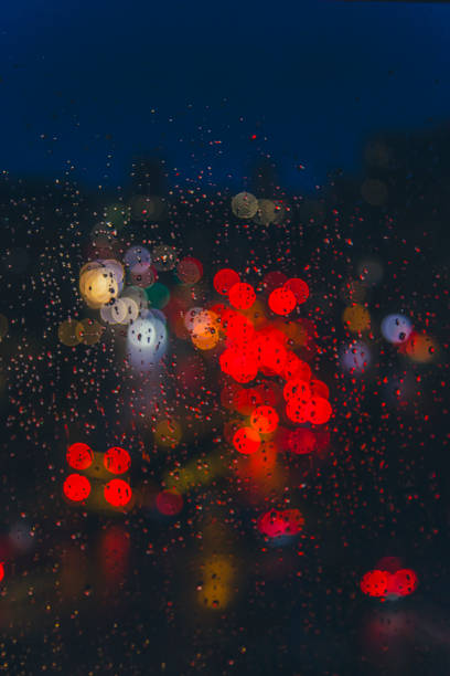 rain drops on window surface with colorful traffic bokeh light in background