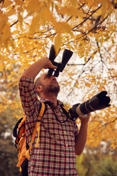 istock Man using binoculars and camera for bird and animal watching in nature. 2173888062