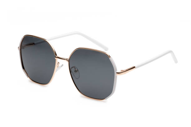 istock Pair of modern sunglasses with a white and gold frame is lying on a white background, showcasing their stylish design 2173889202