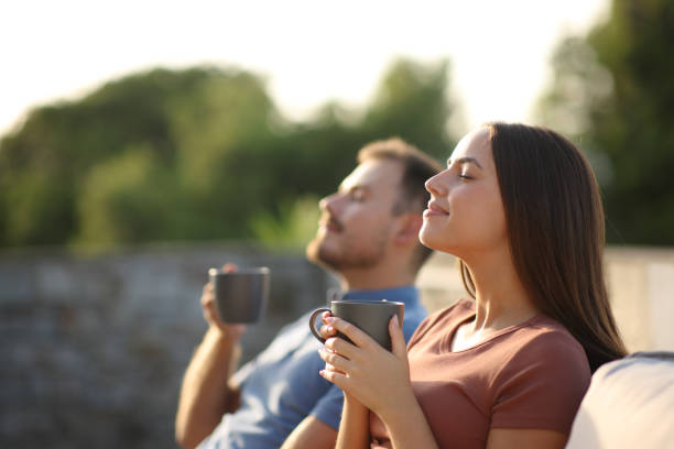 Couple drinking coffee and breathing in a terrace stock photo