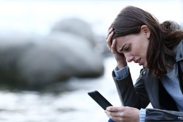 istock Sad woman complaining checking mobile phone on the beach 2173899258