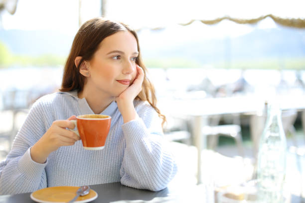 istock Distracted woman drinking coffee in a bar terrace 2173899306