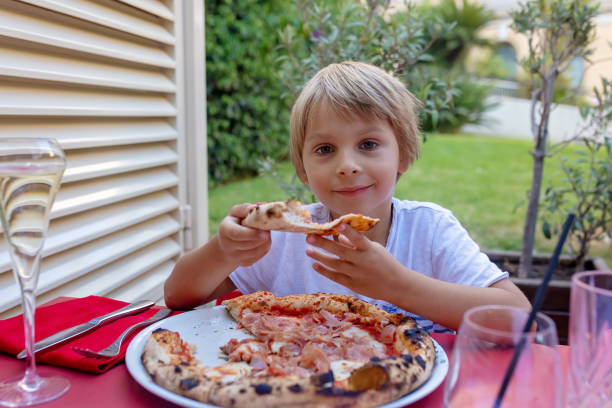 istock Child, eating pizza and burger in restaurant, summertime 2173907482