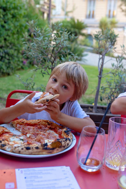 istock Child, eating pizza and burger in restaurant, summertime 2173907533