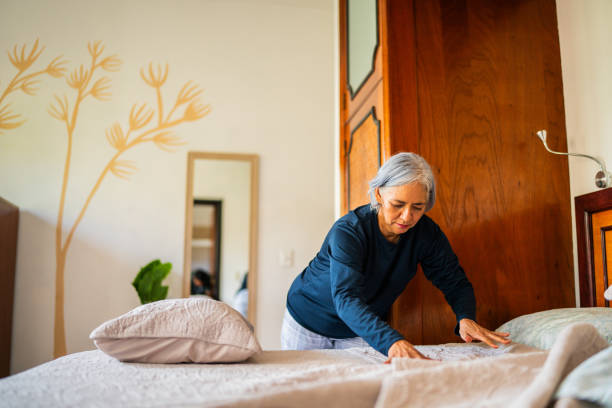 Senior woman making the bed at home