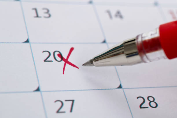 Hand holding felt tip pen and April 2019 calendar on desk
