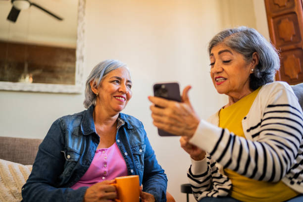 Senior friends talking and using mobile phone at home