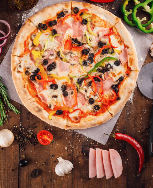 istock Delicious pizza lying on wooden table surrounded by fresh ingredients 2173922626