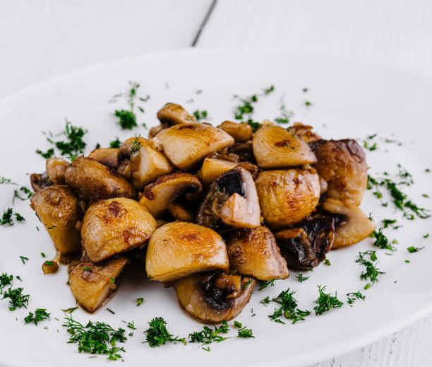 istock Fried mushrooms with dill lying on white plate on white table 2173923753