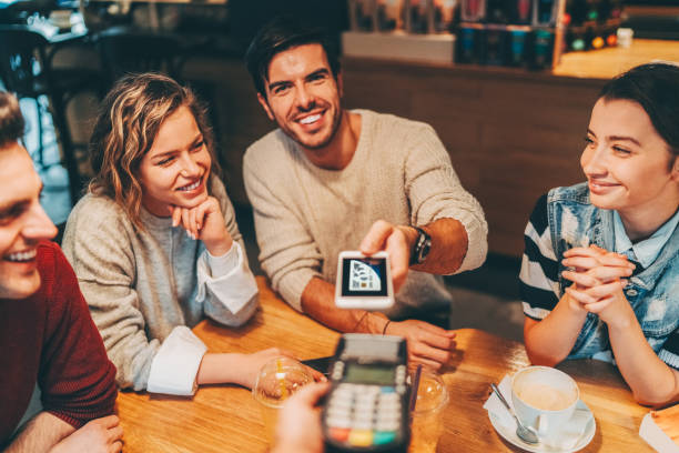 istock Smiling man with friends at cafe paying with smartphone 2173926687