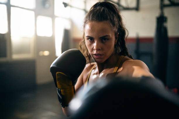 istock Focused female kickboxer shadowboxing during practice in the gym 2173926774