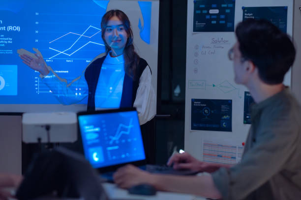 istock asian leader present  business presentation in a dimly lit office, analyzing financial charts and data projections on a screen 2173928363
