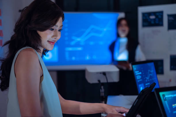 istock asian leader present  business presentation in a dimly lit office, analyzing financial charts and data projections on a screen 2173928449