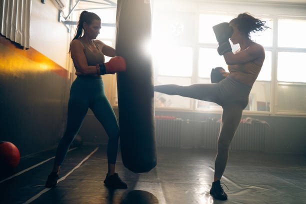 istock Strong female kickboxer kickign th epunching bag, during practice with coach 2173929627