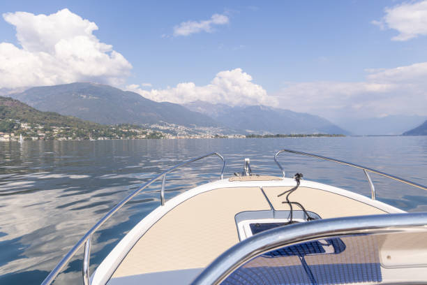 A peaceful boat ride on a calm mountain lake, surrounded by majestic peaks and soft clouds. Clear skies and reflections create a serene atmosphere.