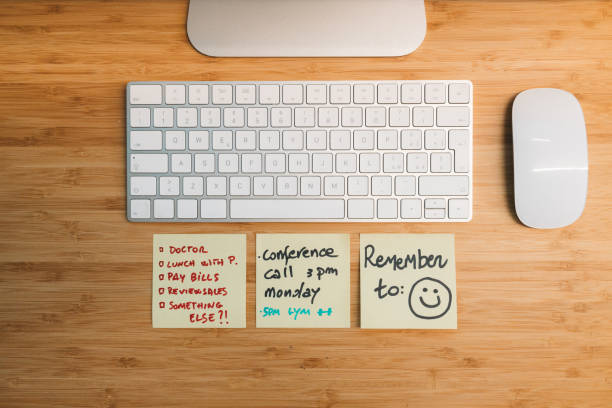 Clean wooden desk with a computer keyboard and mouse is shown with sticky notes reminding someone of appointments
