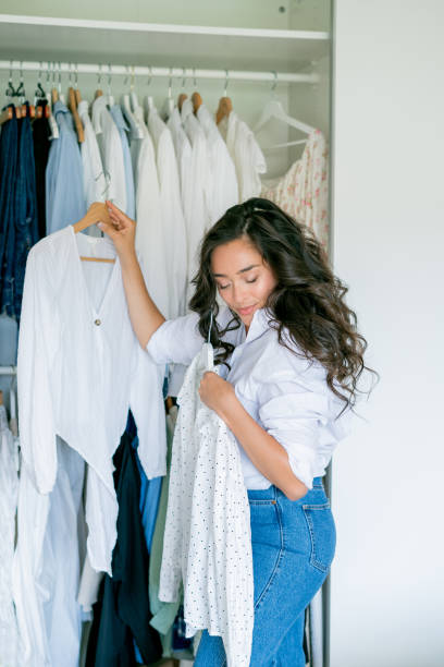 istock Young dark-haired curly beautiful woman is sorting things in large spacious closet. Home organization. Washing things. Analysis of clothes by season. 2173949430