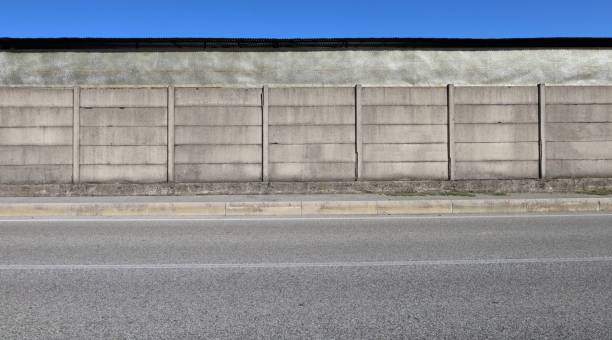 istock Concrete precast compound wall at the road side with fiberglass panel wall on behind, cement sidewalk and street in front. 2173949444