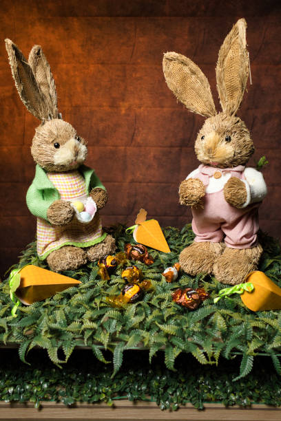 istock Two stuffed rabbits are sitting on a green carpet with carrots 2173950470