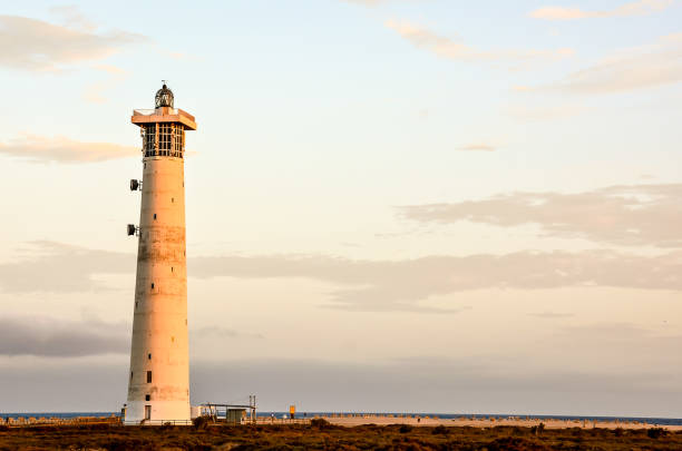 istock A lighthouse is standing on a beach with a cloudy sky in the background 2173950785