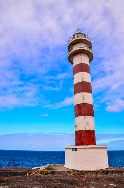 istock A lighthouse is standing on a rocky shoreline, overlooking the ocean 2173950873
