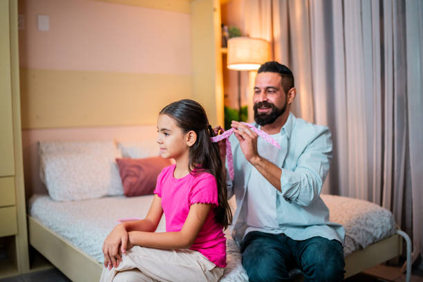 istock Father tying daughter's hair at home 2173952659