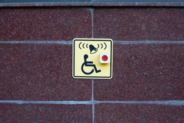 Wheelchair sign next to button to call help on street wall. Accessible area for people with disabilities, moving people in wheelchairs in modern city