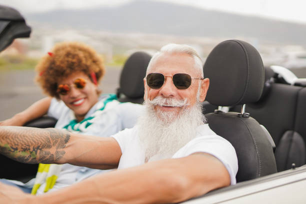 istock Happy senior multiracial couple having fun on a road trip during summer vacation inside convertible car - Healthy elderly lifestyle - Focus on man face 2173954520
