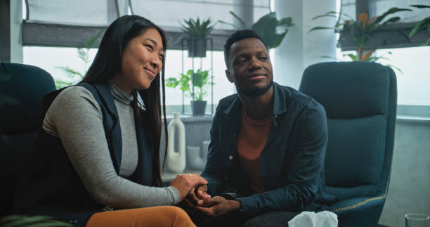 istock Happy multiethnic couple sit on chairs holding hands after quarrel on couples therapy 2173955431