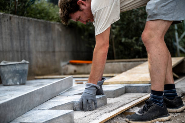 istock Manual worker paving backyard with concrete tiles 2173959526