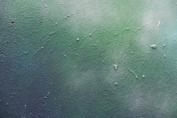 Close-up of an abstract surface with green and yellow brushstrokes, accented by small holes. The image showcases the varied textures and vibrant colors, creating a dynamic and artistic composition.