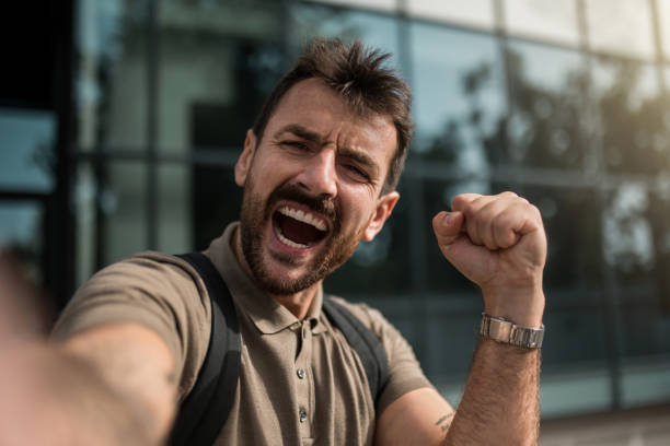 istock Young man taking a selfie and celebrating while standing next to an office building. 2173964483