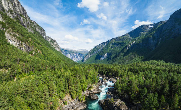A a clear, flowing river amidst dense green forests. The name of the river is Rauma and the location of this spot is 10 km away from the city of Åndalsnes in northern Norway. It resembles of both Yosemite Valley in USA and the landscapes of the southern island in New Zealand.