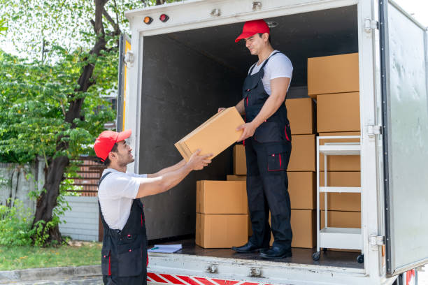istock Caucasian young delivery man delivering package to customer at home. Attractive courier postman worker in red uniform working, loading deliver box cardboard postal from car truck infront of the house. 2173968449