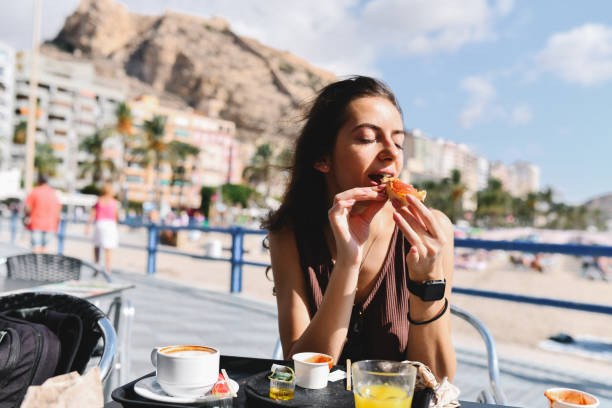 istock Beautiful Female Sitting At A Spanish Beach Bar While Drinking Coffee And Eating Breakfast 2173971356