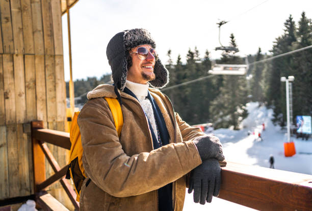 Young happy man enjoying the view on a beautiful cold winter day at ski resort on mountain