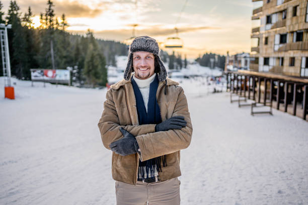 Portrait of a young cheerful man enjoying at ski resort on the mountain