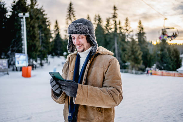 istock Young man using phone at a ski resort on the mountain 2173976981