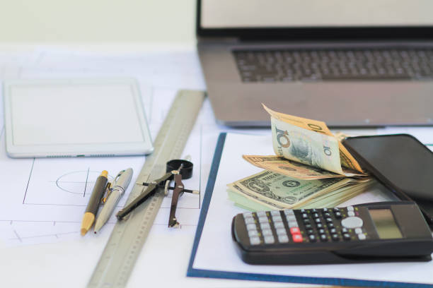 istock Engineers and Foreman are calculating workers' expenses and overtime to pay workers compensation and overtime each month. Foreman holds cash in hand to pay workers as compensation 2173981159